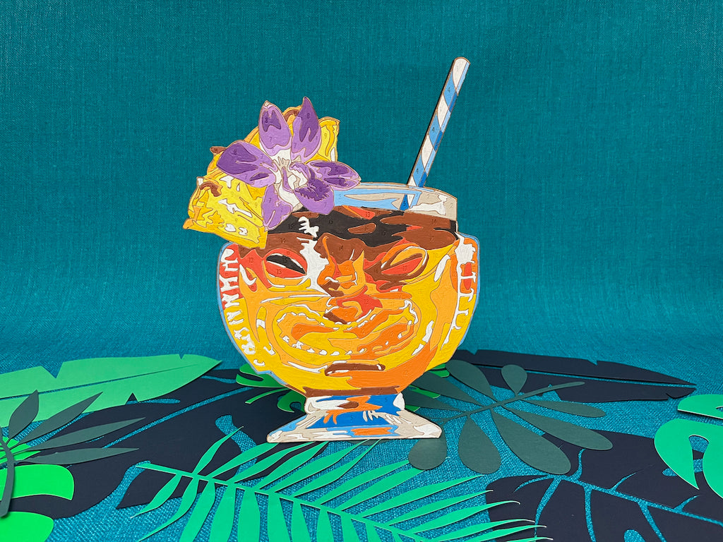 Tiki Lovers UNITE! The new Tiki Time Paint by Numbers collection features four beautiful drinks. The Mia Tia is presented in the smiling side of a two faced tiki glass. There's a clear striation of the various rums used in this cocktail to make your mouth water as you paint! A pineapple wedge and an orchid flower adorn the rim. Sticking out to the left is a classic blue and white striped paper straw!