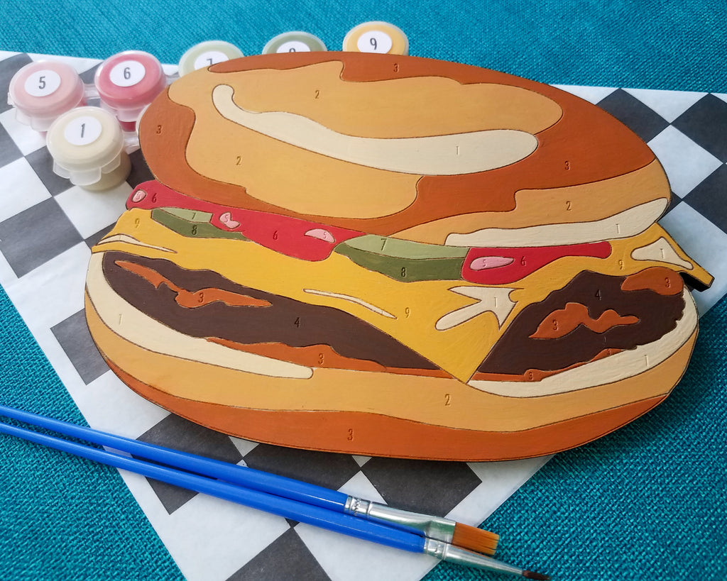 The Cheeseburger Paint by Number kit is a simpler design, perfect for younger artists. On the back of the canvas there is a hook so you can proudly display your finished paint by number on the wall.